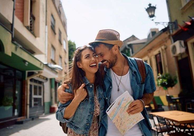 Pareja feliz explorando ciudad europea con mapa, disfrutando de sus viajes